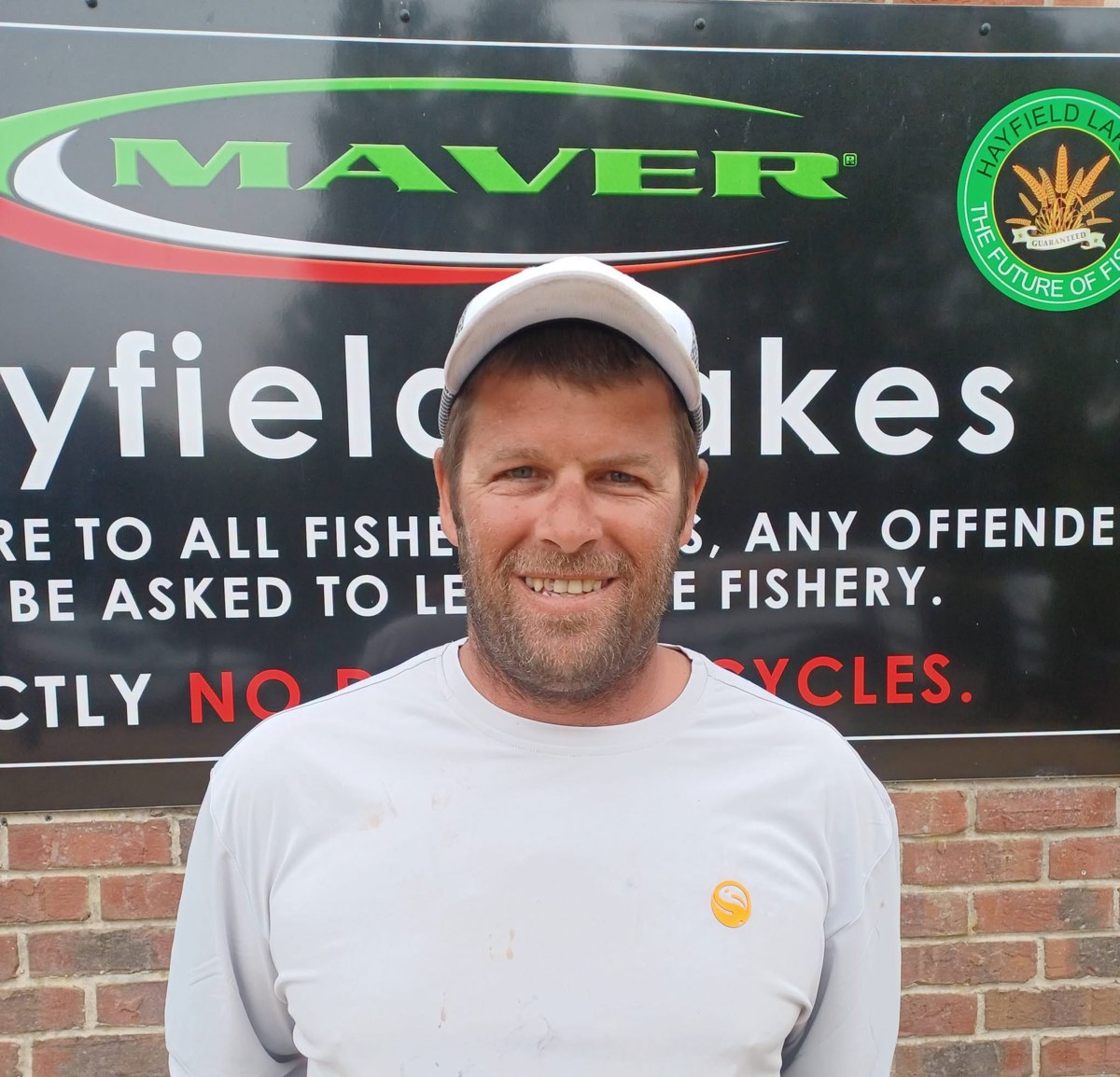 Dale Shepherd smiling in front of a fishery sign.